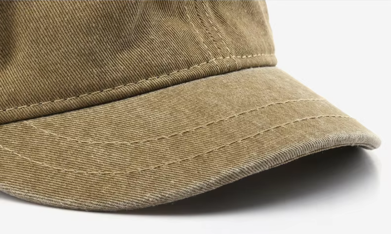 Close-up of a washed brown logo-free baseball cap brim, showing textured cotton fabric and vintage-inspired stitching detail on a white background.